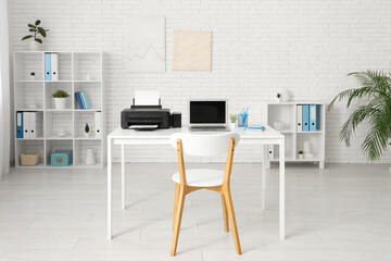 Stylish workplace with modern printer and laptop in light home office