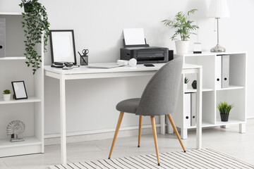 Stylish workplace with modern printer, mobile phone and laptop in light home office