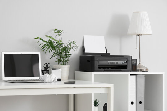 Stylish workplace with modern printer and laptop in light home office