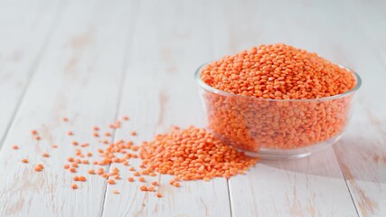 red lentils in a glass plate and scattered on a white wooden table. organic red lentils in a clear glass bowl on a light kitchen table. - Powered by Adobe