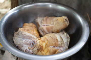 A person is cooking meat in a bowl with gloves on. The person is wearing a blue apron
