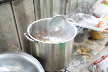 A person is cooking meat in a bowl with gloves on. The person is wearing a blue apron

