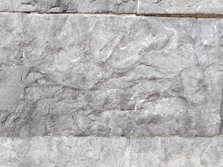 Gray natural stone surface texture on the exterior wall of a building.