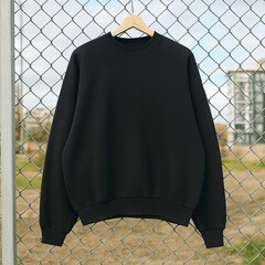Black Sweatshirt hanging on hanger on metal fence with urban cityscape