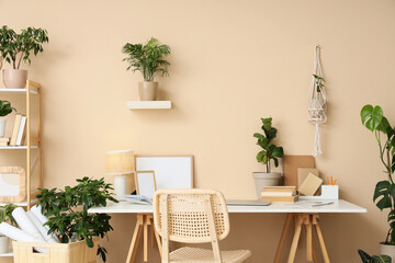 Interior of stylish office with comfortable workspace, books, modern laptop and houseplants