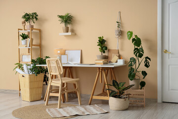 Interior of stylish office with comfortable workspace, books, modern laptop and houseplants