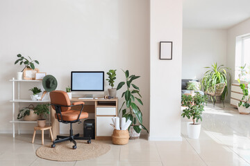 Interior of light office with comfortable workspace, modern computer and houseplants