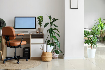 Interior of light office with comfortable workspace, modern computer and houseplants