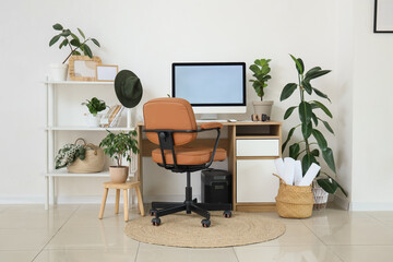 Interior of light office with comfortable workspace, modern computer and houseplants