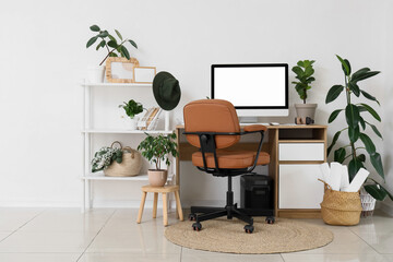 Interior of light office with comfortable workspace, modern computer and houseplants
