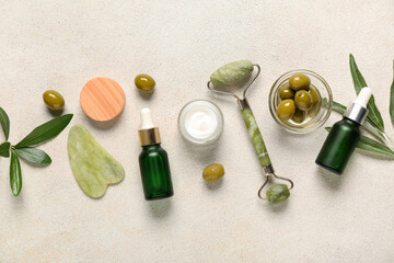 Composition with natural cosmetic products, facial massage tools and green olives on light background