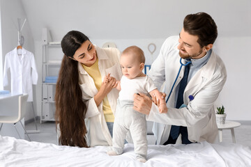 Fototapeta premium Mother and pediatrician with stethoscope listening to baby in clinic