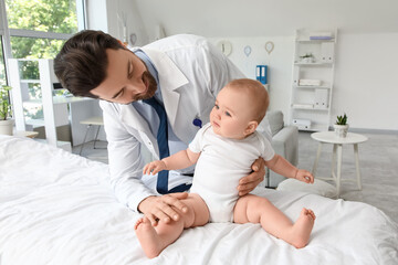 Obraz premium Male pediatrician with little baby on couch in clinic