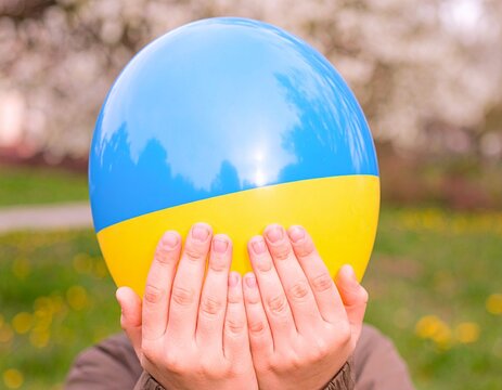 hands holding ukraine flag colored ball outdoors - Powered by Adobe