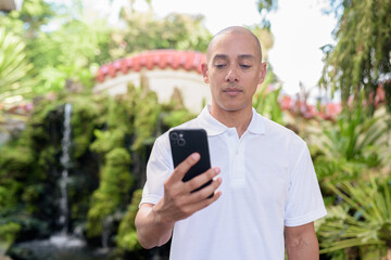 Fototapeta premium Modern man in Zen garden using smartphone, blending nature and technology