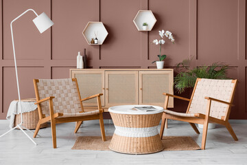Interior of stylish living room with wooden armchairs, table and commode