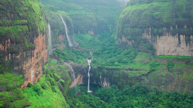 4K Slow motion shot of Devkund waterfall falling from a cliff of the Sahyadri mountain during the monsoon season as seen from Savlya Ghat view point in Raigad district, Maharashtra, India. Scenic view