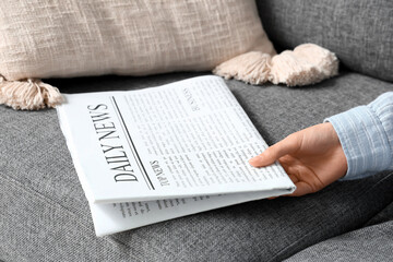 Female hand with newspaper on sofa, closeup