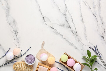 Bath bombs with sea salt, soap, massage brush and lavender flowers on marble background
