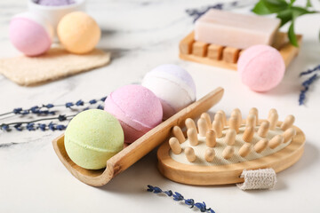 Bath bombs with massage brush and lavender flowers on marble background, closeup