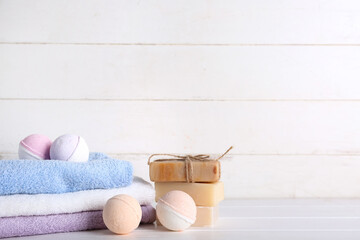 Bath bombs with towels and soap bars on white wooden table, closeup