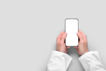Doctor's hands with blank mobile phone on light background