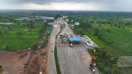 aerial view of highway toll plaza chhattisgarh, drone shot of national highway toll gate india, traffic at toll collection point surrounded by greenery, infrastructure and transportation stock photo. 
