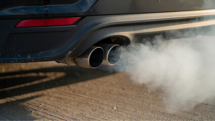 Black car exhaust pipes emitting white smoke emission