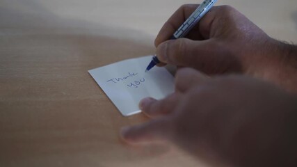 Caucasian man writing a thank you note and a smiling face with a ballpen on white paper. - Powered by Adobe