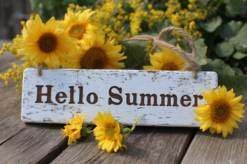A white sign with yellow flowers and the words "Hello Summer" written on it