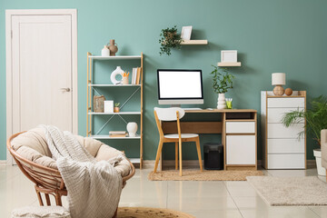 Interior of stylish living room with armchair, comfortable workspace, modern computer and houseplants