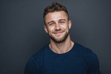 Obraz premium Up-close portrait of a cheerful young man wearing a blue t-shirt against a grey backdrop