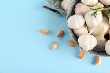 Bowl with fresh garlics and rosemary on blue background