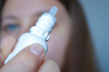 woman applying eye drops for dryness relief. themes: eye care, healthcare routine, vision treatment, self-care, ophthalmology, personal hygiene.