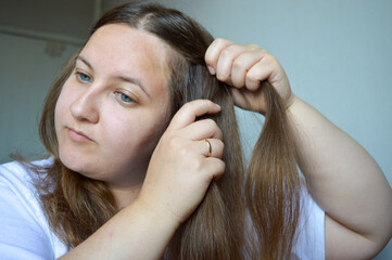 Fototapeta premium woman braiding her long hair, focusing on hands and strands. themes: beauty routine, hair care, hairstyle tutorial, self-grooming, personal hygiene, daily habits.