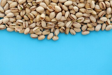 Tasty unpeeled pistachios on bright blue background, top view flat lay background pattern