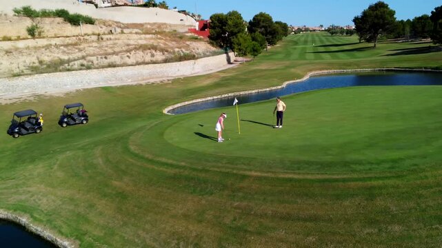 Golfers putting on green in picturesque golf course