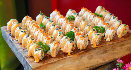 Japanese food buffet Sushi Salmon Roll Garnish with vegetables Beautifully arranged on a wooden tray. At a luxurious hotel restaurant.