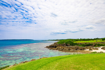爽やかな南国の青空とサンゴが映える海が見えるリゾートゴルフ場の海越えホール（沖縄県宮古島市）
