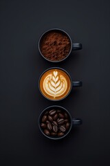 Overhead view of three cups filled with ground coffee, latte art, and coffee beans on a black background.