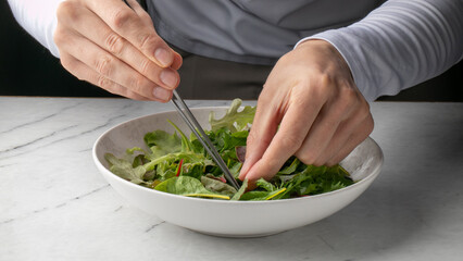 Erasing tiny worlds of verdant mystery, a Caucasian male hands curate spring salad symphony, evoking Earth Day mindfulness