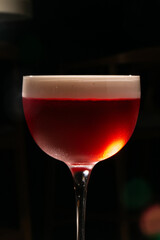 A ruby-hued cocktail gleams under moody lighting, perfect for Carnaval festivities and obscure mixology nights