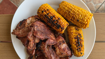 Grilled corn, ashen-charred mementos of midsummer revelry, nesting beside hearty carnivore slices,...