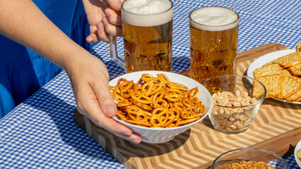 A cheerful Caucasian man enjoys Oktoberfest delicacies with foamy beer, salted pretzels, and sunlit...