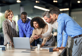 Successful businesspeople working in a coworking space working with laptop discussing strategy and business plan in modern office.