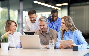 Obraz premium Successful businesspeople working in a coworking space working with laptop discussing strategy and business plan in modern office