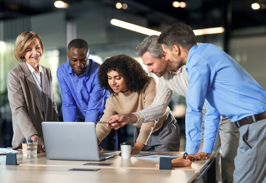 Successful businesspeople working in a coworking space working with laptop discussing strategy and business plan in modern office. - Powered by Adobe