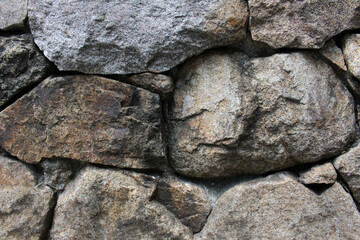 Close up of natural stone wall texture. Rough surface of stacked stones in different colors and shapes background.