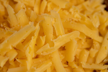 grated cheese for cooking and folded into a wooden bowl, close up