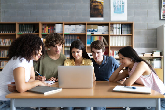 High school students working together on laptop in library